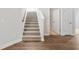 Carpeted staircase with white risers and a wooden handrail is situated next to a hardwood floor entryway and several doors at 2480 Campton Loop, Conway, SC 29527