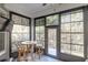 Bright sunroom features walls of windows, a bistro table, two chairs and views of the surrounding landscape at 138 Sugar Loaf Ln., Murrells Inlet, SC 29576