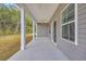 A covered back porch featuring white columns, a concrete floor, and views of the wooded backyard at 240 Palmetto Sand Loop, Conway, SC 29527