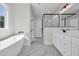 Bright bathroom featuring a soaking tub, glass-enclosed shower, double vanity, and marble-look tile at 604 Mccown Dr., Conway, SC 29526