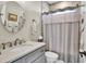 Well-lit bathroom featuring a round mirror, white marble countertop, and a shower with gray and white tile at 253 W Second Ave. S, Ocean Isle Beach, NC 28469