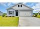 Charming exterior of a light blue home featuring a two-car garage, black shutters, and manicured landscaping at 1044 Jase Dr., Longs, SC 29568