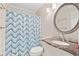 Bathroom featuring a granite vanity top, oval mirror, and a tub with a blue chevron shower curtain at 191 Maison Dr. # B203, Myrtle Beach, SC 29572