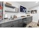 Modern basement wet bar features granite countertops, gray cabinets, open shelving, sink, and sleek appliances for entertaining at 6205 Nixon St., North Myrtle Beach, SC 29582