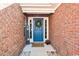 Close-up of a charming blue front door with sidelights, a wreath, and a welcome mat, all framed by brick at 305 Duel Ct., Myrtle Beach, SC 29588