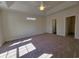 Spacious bedroom with tray ceilings, a ceiling fan, neutral carpeting, and access to closet and bathroom at 2770 Daisy Rd., Loris, SC 29569