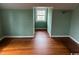 Bedroom with warm hardwood floors, light green paneled walls and window to another room at 2708 Main St., Loris, SC 29569