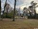 Charming yellow home with a welcoming porch surrounded by mature trees in a large yard at 2708 Main St., Loris, SC 29569