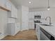 Bright kitchen boasts white cabinets, stainless appliances, wood flooring, and a center island with a sink at 1200 Nw Calabash Station Blvd., Calabash, NC 28467