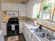 Kitchen featuring white cabinets, tile countertops, stainless appliances, and a garden window at 306 E Godbold St., Marion, SC 29571