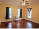 Bright living room with hardwood floors, three large windows, and ceiling fan at 306 E Godbold St., Marion, SC 29571