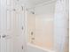 Bright bathroom featuring a bathtub with white shower curtain and a neutral-toned surround at 5900 N Ocean Blvd., North Myrtle Beach, SC 29582