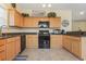 Well-lit kitchen featuring wooden cabinets, granite countertops, and black appliances at 1133 Spalding Ct., Surfside Beach, SC 29575