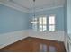 Formal dining room featuring wainscoting, hardwood floors, tray ceiling, and a modern chandelier at 64 Summerlight Dr., Murrells Inlet, SC 29576