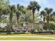 Landscaped entrance sign for Palm Bay featuring lush greenery, flowering plants, and mature palm trees at 64 Summerlight Dr., Murrells Inlet, SC 29576