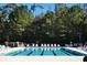 Community pool featuring multiple lap lanes, surrounded by lounge chairs, lush landscaping, and mature trees at 64 Summerlight Dr., Murrells Inlet, SC 29576