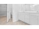 Bathroom featuring dual sinks, white cabinets, and a walk-in closet beyond a partially open door at 1233 Nw Calabash Station Blvd., Calabash, NC 28467