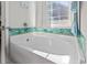 Clean white bathtub with coastal tile accents and a bright window for natural light at 724 Hobonny Loop, Longs, SC 29568