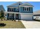 Charming two-story home featuring a two-car garage, manicured lawn, and stylish blue siding at 574 Haven View Way, Murrells Inlet, SC 29576