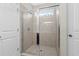 Tiled walk-in shower stall featuring glass doors, neutral tile, and a window at 1711 Sapphire Dr., Longs, SC 29568