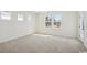 A light-filled room, featuring neutral carpet and paint, is brightened by three windows and a glass door at 2624 Hillbourne Loop, North Myrtle Beach, SC 29582