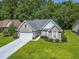 Aerial view of a brick home with a spacious lawn and a two car garage in a lush neighborhood at 765 Ashley Manor Dr., Longs, SC 29568