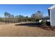 Spacious backyard with lush grass leading to a serene pond, framed by mature trees at 405 White Willow Way, Longs, SC 29568