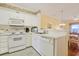 Well-lit kitchen featuring white cabinets and appliances, with an adjoining dining area for convenient meals at 4240 Coquina Harbour Dr. # E-4, Little River, SC 29566