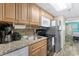 A compact kitchen featuring granite counters, stainless steel appliances, and wood cabinets at 2311 S Ocean Blvd. # 1125, Myrtle Beach, SC 29577