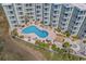 Aerial view of a kidney-shaped pool and jacuzzi surrounded by greenery and multiple seating areas at 9400 Shore Dr. # 312, Myrtle Beach, SC 29572