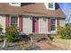 Charming home exterior with a red front door, red shutters, symmetrical windows, and neatly landscaped plants at 702 Plantation Dr., Surfside Beach, SC 29575