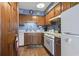 Well-lit kitchen with wood cabinetry, laminate flooring, and white appliances offering a functional cooking space at 702 Plantation Dr., Surfside Beach, SC 29575