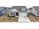 Beige two-story house with a gray roof, white garage door, and landscaping at 1262 Witch Hazel Way, Longs, SC 29568
