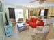 Comfortable living room features a bright orange sofa, two chairs, TV, and sliding glass door to a balcony at 507 S Ocean Blvd. # 201, North Myrtle Beach, SC 29582