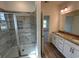 Well-lit bathroom with double sink vanity, tiled shower with glass door, and wood-look flooring at 541 Honeyhill Loop, Conway, SC 29526
