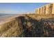 Beach view of a beautiful condo complex on a sandy beach with dune grass in front at 645 Retreat Beach Circle, Pawleys Island, SC 29585