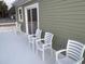 Covered patio area featuring a row of white chairs along a green house, perfect for outdoor relaxation at 931 Edge Dr., North Myrtle Beach, SC 29582