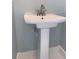 Close-up of a pedestal sink with a modern faucet in a minimalist powder room, creating a clean aesthetic at 931 Edge Dr., North Myrtle Beach, SC 29582