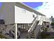 View of home's exterior, showing stairs to front deck, covered parking, and surrounding landscaping at 9620 Windchime Dr., Myrtle Beach, SC 29572