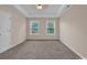 Spacious bedroom with neutral walls, tray ceiling, plush carpet, and natural light from two large windows at 4672 Lightkeepers Way # 50-E, Little River, SC 29566