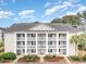 Two-story condo building with light beige exterior, white columns, and balconies at 5010 Windsor Green Way # 301, Myrtle Beach, SC 29579