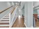 Bright foyer with wood-look tile floors leads to a staircase with wood and white risers and a hallway with a decorative chair at 1405 Osprey Pointe Ln., North Myrtle Beach, SC 29582