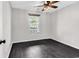 An airy bedroom with sleek, dark hardwood floors, a ceiling fan, and a bright window at 1900 Shell Ct., Surfside Beach, SC 29575