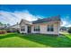 Back of the home displays neutral siding, multiple windows, green lawn, and a serene surrounding landscape at 4382 Saint Annes Ct., Myrtle Beach, SC 29579