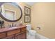 Powder room has a granite countertop vanity, a round beveled mirror, a commode and is decorated with framed art at 9547 Edgerton Dr. # 904, Myrtle Beach, SC 29572
