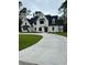 Two-story house with white brick exterior, black roof, and a large driveway at 101 Green Lake Dr., Myrtle Beach, SC 29572