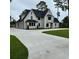 White farmhouse-style home with a three-car garage and landscaping at 101 Green Lake Dr., Myrtle Beach, SC 29572