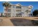 Condo building with stone and yellow siding, balconies, and palm trees at 4687 Wild Iris Dr. # 103, Myrtle Beach, SC 29577