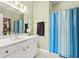 Bright bathroom with a white vanity, mirror, and a shower with a blue-striped curtain at 2080 Cross Gate Blvd. # 303, Surfside Beach, SC 29575