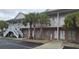 A two-story building with brick facade, palm trees, and white staircases leading to the second floor at 241 Presidential Dr., Surfside Beach, SC 29575